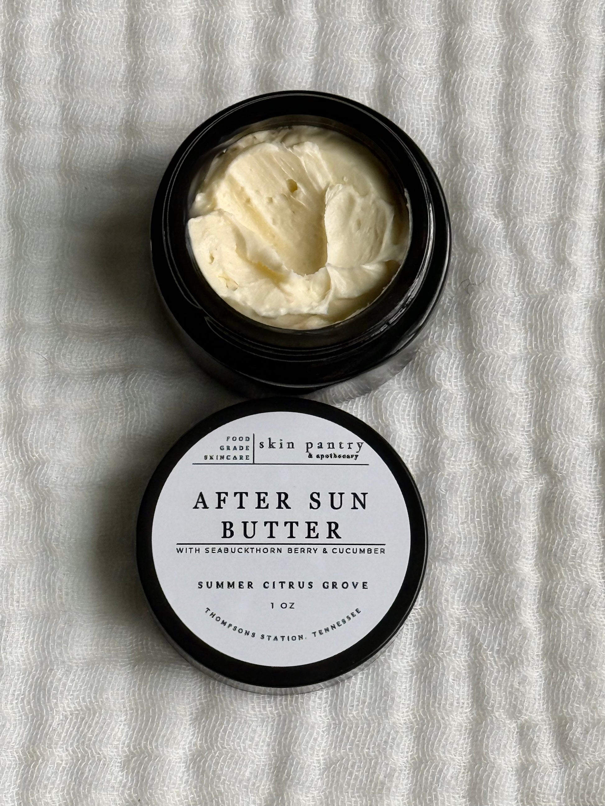 Open jar of after sun butter with a label on a textured white background