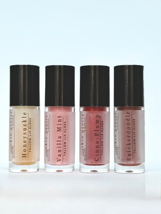 Four lip gloss bottles with black caps on a light blue background