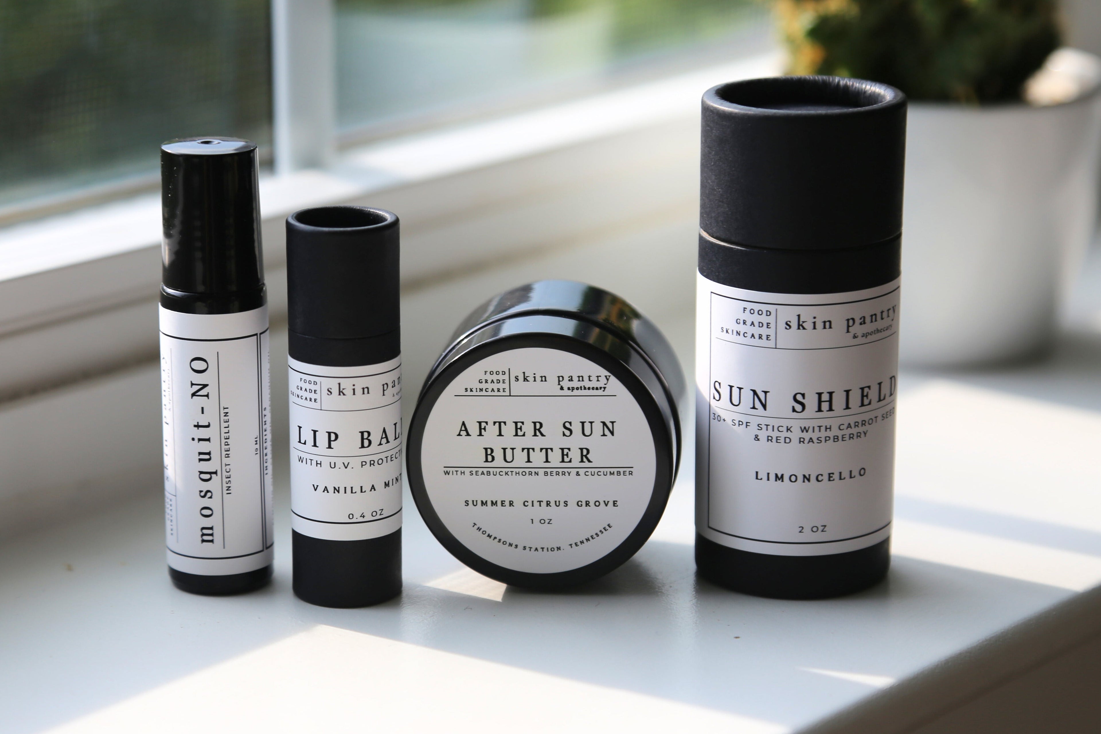Collection of skincare products on a windowsill with natural light.